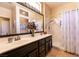 Bathroom with dual sinks, white countertops, dark cabinetry, a large mirror, and a shower-tub combo at 2521 Roseworthy Dr, Las Vegas, NV 89134