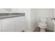 This half-bathroom has a white vanity with gray countertop, a toilet, and neutral-colored tiling at 3041 Gary Cooper St # 103, Las Vegas, NV 89122