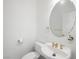 Powder room featuring a pedestal sink with a round mirror, toilet, and golden hardware at 3431 Cottage Thistle Dr, Laughlin, NV 89029