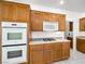 Close up of kitchen featuring stainless oven, microwave, wood cabinets, and light countertops at 3431 Cottage Thistle Dr, Laughlin, NV 89029