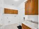 Functional laundry room features oak cabinets and a utility sink with white tiling at 3431 Cottage Thistle Dr, Laughlin, NV 89029