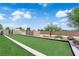A well-maintained backyard featuring a strip of green lawn, bordered by landscaping and a stone wall, under a clear blue sky at 4455 W Ford Ave, Las Vegas, NV 89139