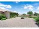 A serene backyard with a paved patio and stone fire pit, set against lush landscaping and a clear blue sky at 4455 W Ford Ave, Las Vegas, NV 89139