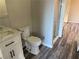 Bathroom featuring grey wood-look floors, white vanity, toilet, and tiled shower stall at 4455 W Ford Ave, Las Vegas, NV 89139