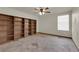 Bright bedroom featuring a ceiling fan, a window for natural light, and built-in wooden bookshelves at 4455 W Ford Ave, Las Vegas, NV 89139