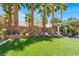 Lush backyard featuring manicured landscaping, palm trees, and a covered patio area at 5785 Farmhouse Ct, Las Vegas, NV 89141