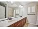 Bathroom featuring double sinks, a large mirror, marble countertops, and a window with plantation shutters at 6409 Shawnee Springs Ct, Las Vegas, NV 89139