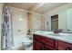Well-lit bathroom with a shower-tub combo, marble countertop, and wood vanity at 6409 Shawnee Springs Ct, Las Vegas, NV 89139
