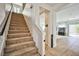 Carpeted stairs with dark handrail leads to open layout room featuring tile floors and view to the backyard at 6409 Shawnee Springs Ct, Las Vegas, NV 89139