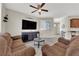 Cozy living room featuring comfortable sofas, a ceiling fan, large windows and a modern entertainment center at 6626 Seahorse Reef St, Las Vegas, NV 89149