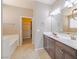 Bathroom featuring a double vanity with a large mirror, tile floors, a large bathtub, and an open closet at 7525 Campbell Ranch Ave, Las Vegas, NV 89179