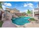 Beautiful pool with waterfall feature, surrounded by lush landscaping and cozy seating at 8268 Nelson Ridge Ln, Las Vegas, NV 89178