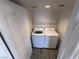 Laundry room with a white washer and dryer; features overhead shelving and a closed door at 8455 W Sahara Ave # 213, Las Vegas, NV 89117