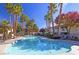 Inviting community pool surrounded by lounge chairs and lush palm trees on a sunny day at 8455 W Sahara Ave # 213, Las Vegas, NV 89117