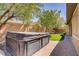 Backyard with a covered hot tub, lush green artificial turf, and mature trees, creating a private outdoor space at 8544 Garden Valley Ct, Las Vegas, NV 89178