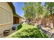 Expansive backyard featuring artificial turf, mature trees, a hot tub, a covered patio, and manicured landscaping at 8544 Garden Valley Ct, Las Vegas, NV 89178