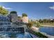 Stone waterfall feature with lush greenery flowing into a serene lake at 8591 Heather Downs Dr, Las Vegas, NV 89113