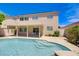 A backyard pool with a covered patio and a two-story house with light colored walls under a bright blue sky at 8913 Loggers Mill Ave, Las Vegas, NV 89143