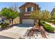 A charming two-story house with a two-car garage, complemented by trees and low shrubs at 9537 Michelle Falls Ave, Las Vegas, NV 89149