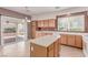 Well-lit kitchen with tile flooring, a center island, light wood cabinets and sliding glass door to the patio at 9537 Michelle Falls Ave, Las Vegas, NV 89149