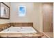 Relaxing bathroom showcasing soaking tub with stone detailing, next to an adjacent glass shower at 1 Cerchio Basso, Henderson, NV 89011