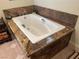 Close-up of a pristine white bathtub with granite surround and modern fixtures at 1 Cerchio Basso, Henderson, NV 89011