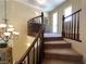 Carpeted staircase with wooden railing, accented by chandelier and upper-level hallway at 1 Cerchio Basso, Henderson, NV 89011