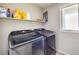 Laundry room with modern washer and dryer units, storage shelves, and a window for natural light at 10623 Auburn Springs Ave, Las Vegas, NV 89166