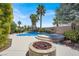 Backyard featuring a pool with an attached spa, fire pit, and lush landscaping at 10805 Hollow Creek Ln, Las Vegas, NV 89144