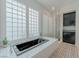 Luxurious bathroom with a soaking tub, walk-in shower, black cabinets, and monochrome mosaic tile flooring at 11477 Timber Mountain Ave, Las Vegas, NV 89135