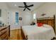 Bedroom with hardwood floors, ceiling fan and a comfortable looking bed near large windows and white closet doors at 11477 Timber Mountain Ave, Las Vegas, NV 89135