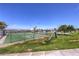 Community tennis court with green surface, net, and surrounding desert landscape and playground at 1157 Morning Sun Way, Las Vegas, NV 89110