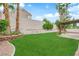 Large backyard featuring lush green grass, a patio, and mature palm trees at 2257 Norway Pine Ct, Las Vegas, NV 89134