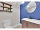 Charming powder room with floating shelves, round mirror and wood vanity at 2257 Norway Pine Ct, Las Vegas, NV 89134