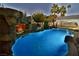 Outdoor pool with rock waterfall, covered seating and palm trees at 2926 E Eldorado Ln, Las Vegas, NV 89120