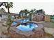 Backyard pool with jacuzzi, rock features, mature palms and a tiki-style bar for outdoor living at 2926 E Eldorado Ln, Las Vegas, NV 89120