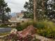 Landscaped entrance featuring lush flowerbeds, decorative rocks, and mature trees at 3005 Treasure Island Rd, Las Vegas, NV 89128