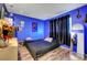 Vibrant blue bedroom featuring wood-look flooring, black accents, and a mirror at 3018 Burnham Ave, Las Vegas, NV 89169