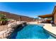 Sparkling pool with rock waterfall feature, set amidst a landscaped backyard, perfect for summer fun at 307 Oak Canyon Dr, Henderson, NV 89015