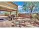 Inviting backyard with a covered patio, a grill, outdoor dining set, and mature shade tree at 3217 Bonassola Ave, North Las Vegas, NV 89031
