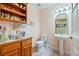 Cozy powder room featuring a pedestal sink, toilet, and charming decor on a wooden shelf at 3640 E Vineyard Dr, Pahrump, NV 89048