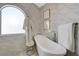 Luxurious bathroom featuring a freestanding tub, arched window, and marble tile surround at 3728 Richard Allen Ct, Las Vegas, NV 89147