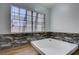 Bathroom featuring a soaking tub beneath a window, with modern wood-look floors and unique marble-look wall paneling at 3928 Edgemoor Way, Las Vegas, NV 89121