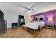 Well-lit bedroom with wood floors, modern furniture, and a vibrant purple accent wall at 3928 Edgemoor Way, Las Vegas, NV 89121