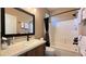 Bathroom showcasing wood-style cabinets, stone counters, and a shower-tub with a black shower curtain at 4299 Fiore Bella Blvd, Las Vegas, NV 89135