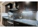 Close up shot of the kitchen with stainless steel appliances, sleek gray backsplash, and dark cabinets at 4576 Amazing View St, Las Vegas, NV 89129