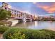 Exterior view of a lakefront community with colorful buildings and a pedestrian bridge at sunset at 52 Reverie Heights Ave, Henderson, NV 89011