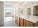 Well-lit bathroom featuring dual sinks, a large mirror, and light gray flooring at 5573 La Perla Ct, Las Vegas, NV 89122