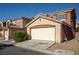 Beige stucco townhome featuring a two-car garage and well-maintained landscaping at 5573 La Perla Ct, Las Vegas, NV 89122