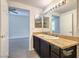 Bathroom featuring double sinks, a large mirror with lighting, and an entry to another room with neutral walls and floors at 8000 Badura Ave # 1168, Las Vegas, NV 89113
